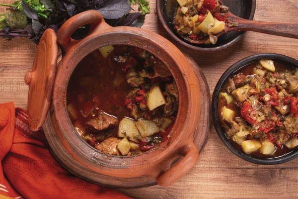 Chanakhi, a Georgian dish. in a clay pot, on a wooden table, stewed meat with vegetables, homemade,