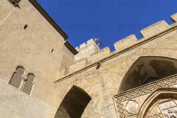 Looking up at historic tower and ramparts in courtyard of historic castle, Aljafería Palace,
