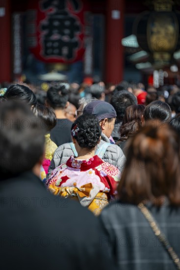 Young Japanese woman wearing kimono surrounded by numerous visitors on Nakamise-dori shopping