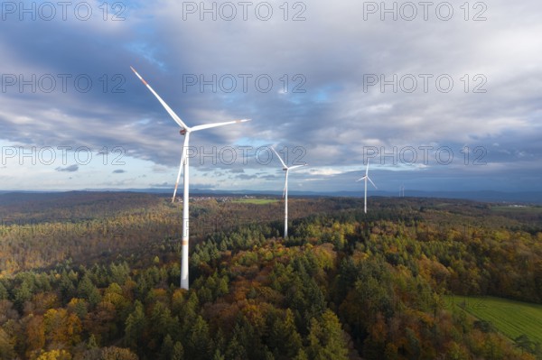 Wind turbines tower above an autumnal forest under a cloudy sky, near Schorndorf, Remstal,