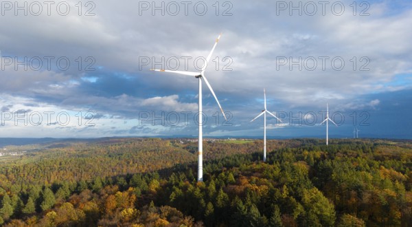 Three wind turbines above a colorful autumn forest against a cloudy sky, near Schorndorf, Remstal,