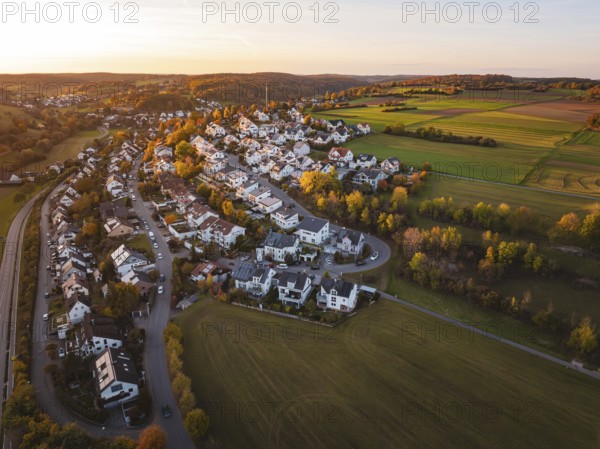 Idyllic landscape at sunset with village and vast fields from a bird's eye view, Deufringen,