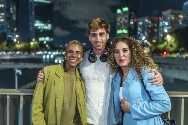 Diverse group of three friends standing arm in arm, smiling at the camera during a casual night out