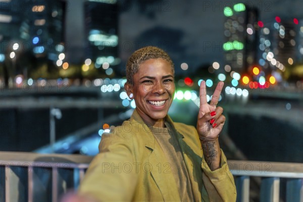 Smiling woman holding up a peace sign, capturing a cheerful selfie moment on a bridge overlooking