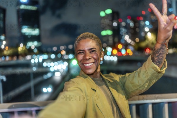 Happy young black woman taking a selfie and showing a peace sign, smiling brightly at camera,