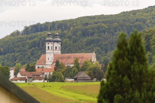 Church with red roofs nestled in green forest and meadow landscape, ZFP Zwiefalten, Reutlingen