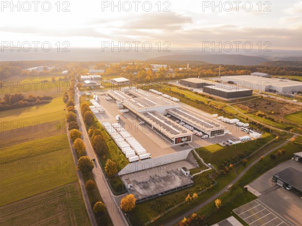 Industrial park with numerous buildings surrounded by green fields and warm skies, Nagold, Black