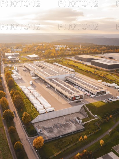 Extensive industrial park with parked trucks and buildings, in colorful late afternoon light,