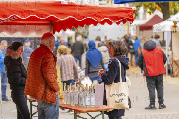 Woman engaged in conversation at a stand with bottles and decorations at a market, traditional