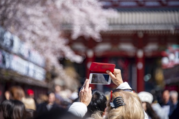 Tourist taking pictures with her cell phone, numerous visitors on Nakamise-dori shopping street,