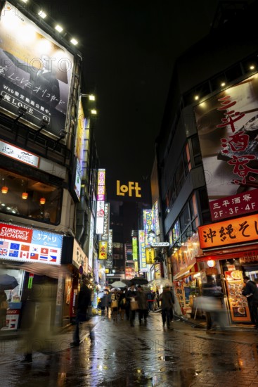 Busy pedestrian zone with many shopping centers and stores, illuminated with lots of neon signs at