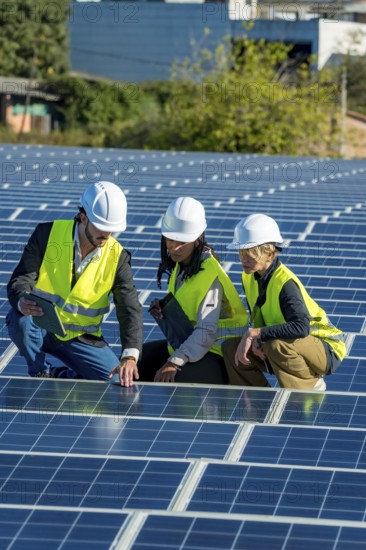 Diverse team of engineers and technicians inspecting and discussing solar panel installation and