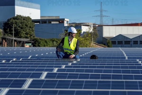 Engineer in a hard hat and high visibility vest inspecting solar panel rows on a large rooftop