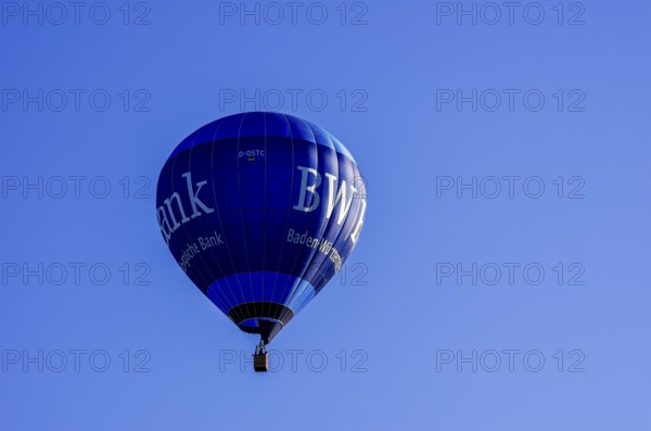 A hot air balloon, registration D-OSTC, rises into the air as part of an air show at the Rossfeld
