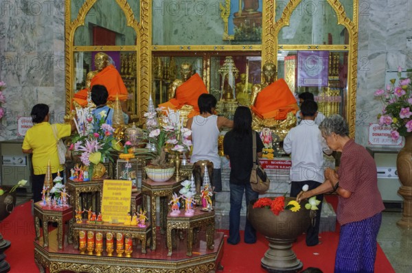 Buddhist believers Buddhists pray making offerings to statues of Buddhist monks covered with gold