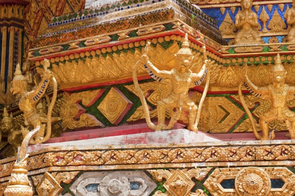 Gilded gold-colored statues figures of Buddhist temple guards mystical guards at Buddhist temple