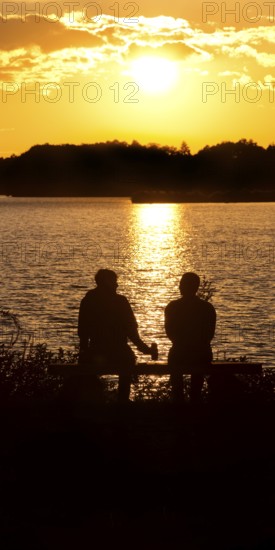 Two men sitting on a bench at sunset at Lake Gudelack, Lindow (Mark), Stechlin-Ruppiner Land nature