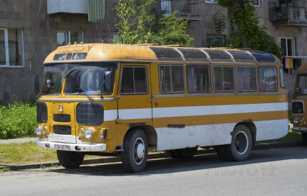 An old retro bus in orange parked on a street next to a building, PAZ-672, minibus from the Soviet