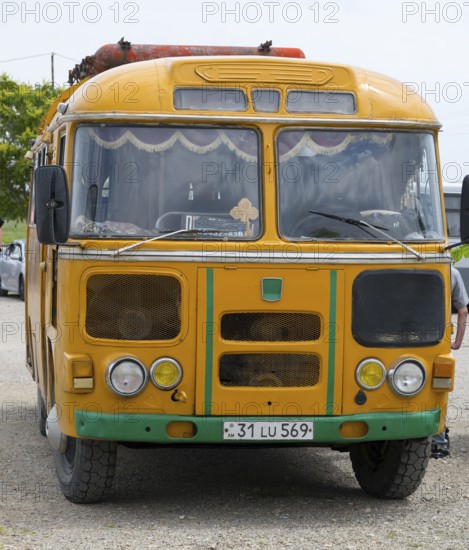 An old orange bus with retro design parked on a street, PAZ-672, minibus from Soviet manufacturer