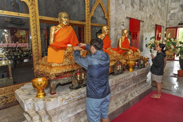Buddhist believers Buddhists pray making offerings to statues of Buddhist monks covered with gold