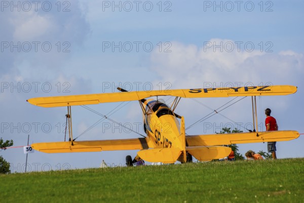 A Bücker Bü 131 Jungmann biplane parked at the edge of the airfield, SP-YPZ registration, as part