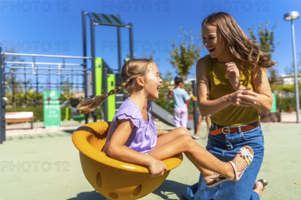 Mother and daughter bonding, laughing, and playing together on a sunny outdoor playground, enjoying