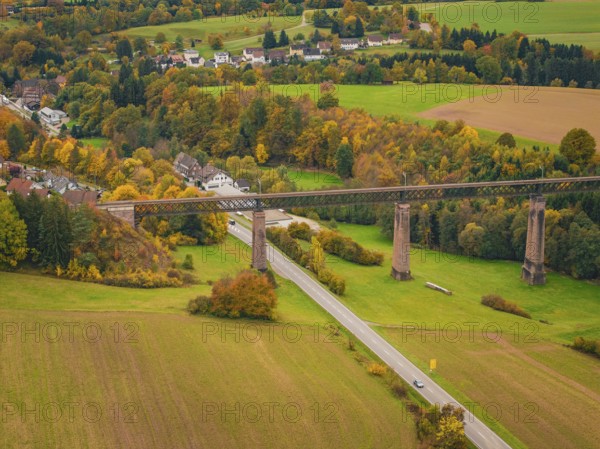 Railway bridge over an autumnal valley with colorful trees and a small village, Dornstetten,