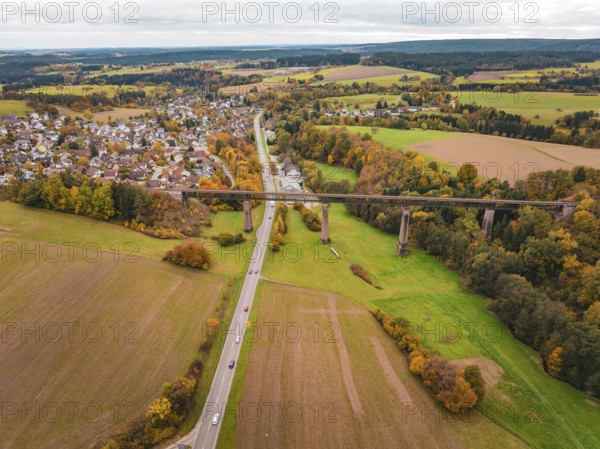 Country road crosses under a bridge in an autumn landscape with fields and villages, Dornstetten,