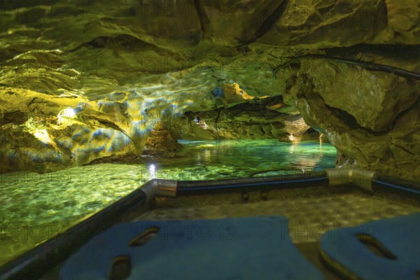 View from a boat of the impressively illuminated interior of a cave with running water, Wimsener