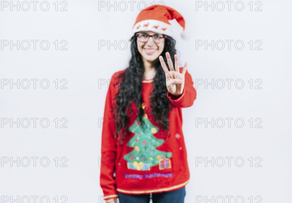 Smiling girl in Christmas sweater counting number 4. Happy girl in Christmas hat counting number