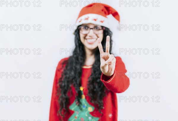 Happy girl in Christmas hat counting number TWO, isolated. Smiling girl in Christmas sweater