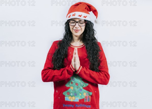 Hopeful Young woman in Christmas sweater making a wish, isolated. Hopeful girl in Christmas hat