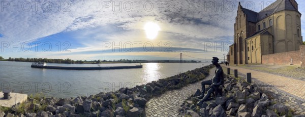 Photo with melancholy mood of bronze sculpture Poortekerl looking at Rhine waiting for ship to