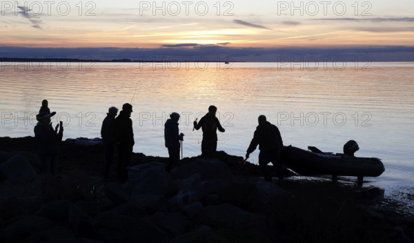Angler on the beach during sunset, an angler docks on the shore with his inflatable boat, Fehmarn