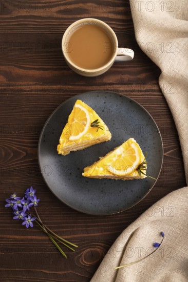Lemon cake on brown wooden background and linen textile, cup of coffee, top view, flat lay, close