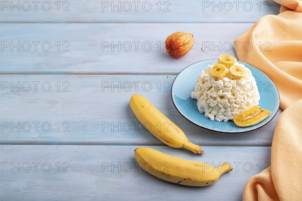White ?ottage cheese, Curd, with Banana on blue wooden background and orange textile, side view,