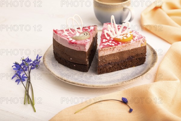 Chocolate cake on white wooden background and orange linen textile, cup of coffee, side view, close