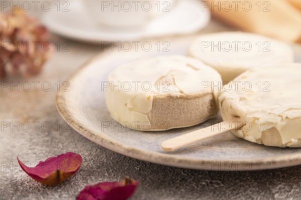 ?hocolate Ice cream in white glaze, cup of coffee, on brown concrete background and orange textile,