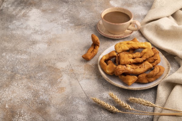 Crunchy biscuit Brushwood cookies sprinkled with powdered sugar on brown concrete background and