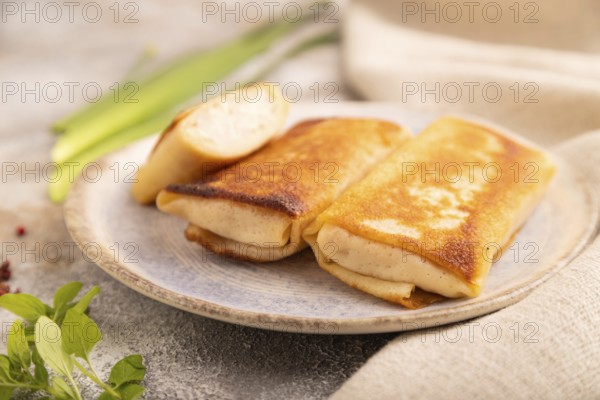 Fried crispy pancakes with meat and cheese on brown concrete background and linen textile. side
