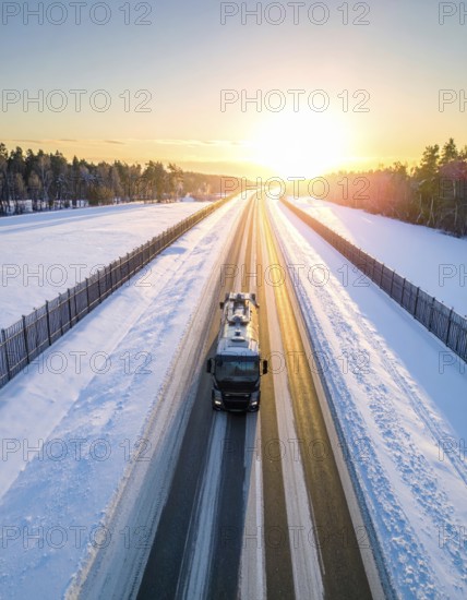 Petrol cargo truck lorry tanker driving on highway hauling oil products at sunrise, wide snowy