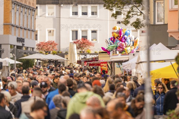 Busy shopping street in autumn, people strolling between modern buildings and colorful shops,