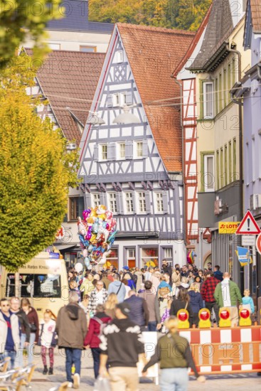 Street festival in the old town with half-timbered houses, people and colorful balloons in autumn,