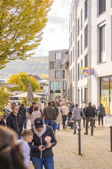A busy street scene in a city, people walking near shops and buildings, Urschelherbst street