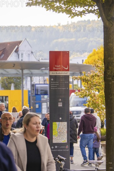 People walk past a bus stop, a signpost shows the way, Urschelherbst Street Festival, Nagold,