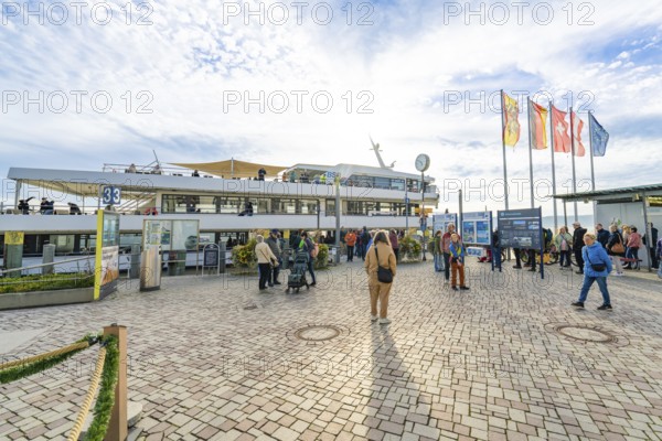 People at the harbor in sunny weather and blue sky, surrounded by flags and ships, Überlingen, Lake