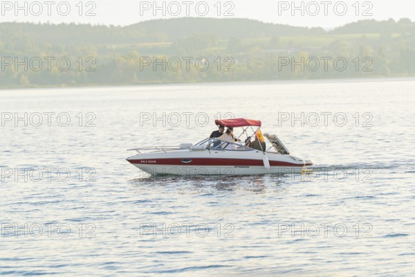 A motorboat with people enjoying a relaxing trip on a quiet lake, Überlingen, Lake Constance,