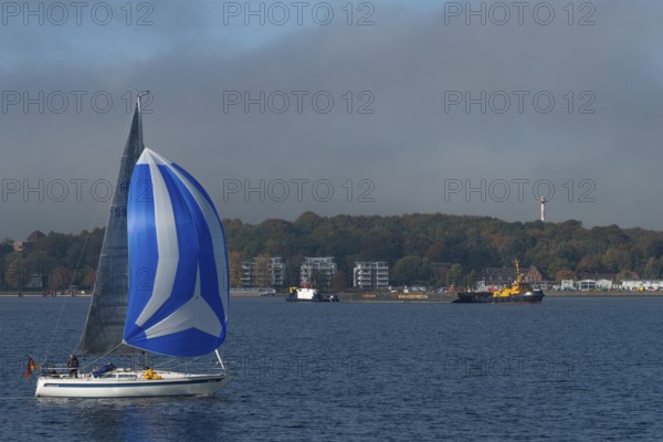 Kiel Fjord, Holtenau district, sailing yacht with spinnaker, tugboat, modern buildings, Kiel,