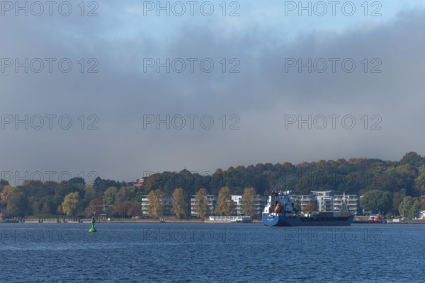 Kiel Fjord, Holtenau district, Kiel, modern apartments on the river bank, cargo ship, hillside,