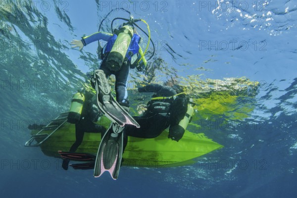 Underwater photo Group of scuba divers climb up to the sea surface at the end of dive on anchor